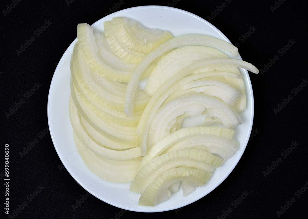 Two bulbs on a black background. Vegetables close-up. Fresh chopped onion. Two bulbs on a black background. Vegetables close-up. Fresh chopped onion.