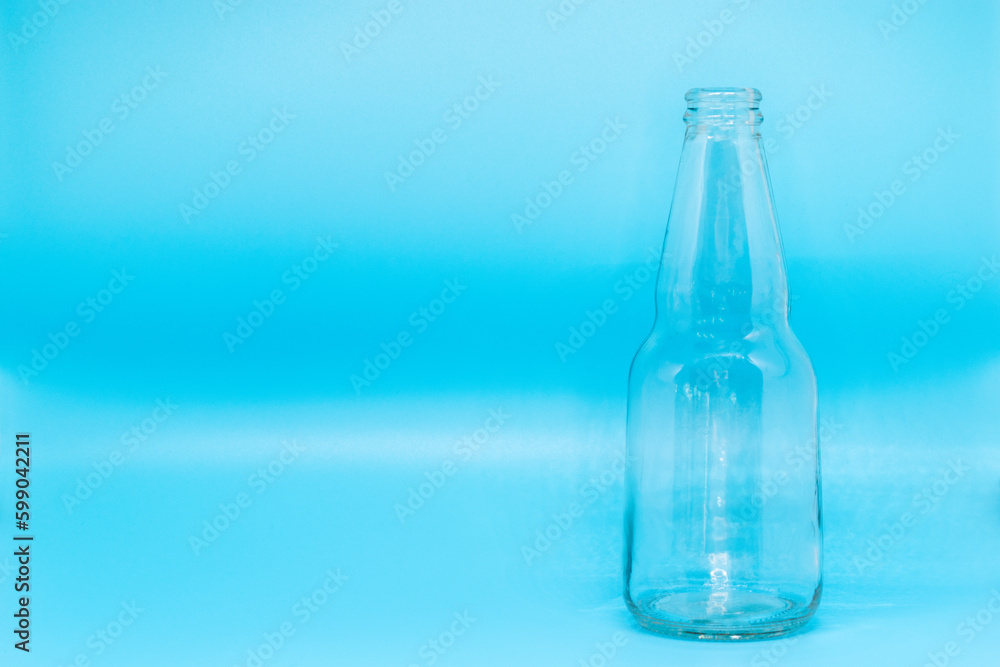 Glass bottle isolated on blue background, beer, soda, sparkling water, juice, label desing, selective focus, front view Glass bottle isolated on blue background, beer, soda, sparkling water, juice, label desing, selective focus, front view