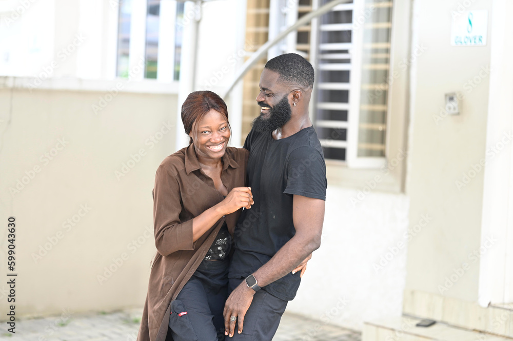 Happy black couple bonding to each other and smiling. Portrait of smiling black man embrace his wife from behind and looking at camera. Portrait of a happy young couple Happy black couple bonding to each other and smiling. Portrait of smiling black man embrace his wife from behind and looking at camera. Portrait of a happy young couple