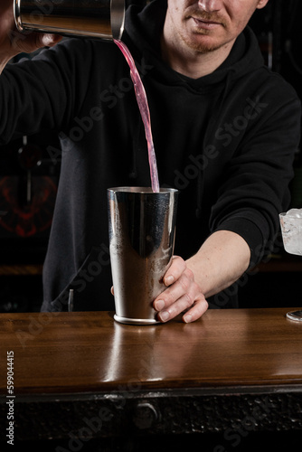 Bartender mixes egg white, lemon, dry vermouth and gin to prepare the Clover club cocktail. Barman prepares classical Clover club alcoholic cocktail at the bar.