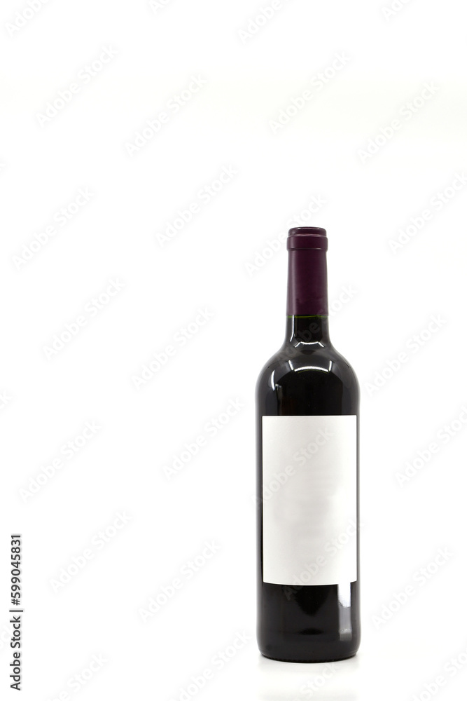 Full unopened bottle of red wine with blank label isolated on a plain white background. Copy space left and above. Full unopened bottle of red wine with blank label isolated on a plain white background. Copy space left and above.
