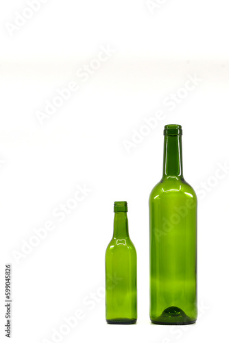 One full size and one quarter empty green wine bottles standing side by side.  isolated on a plain white background. Contrast..