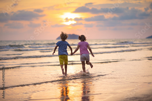 Child playing on ocean beach. Kid at sunset sea.