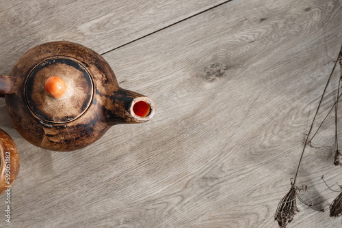 Minimalist wooden table background with handcraft clay teapot and dried flowers, flat lay, copy space