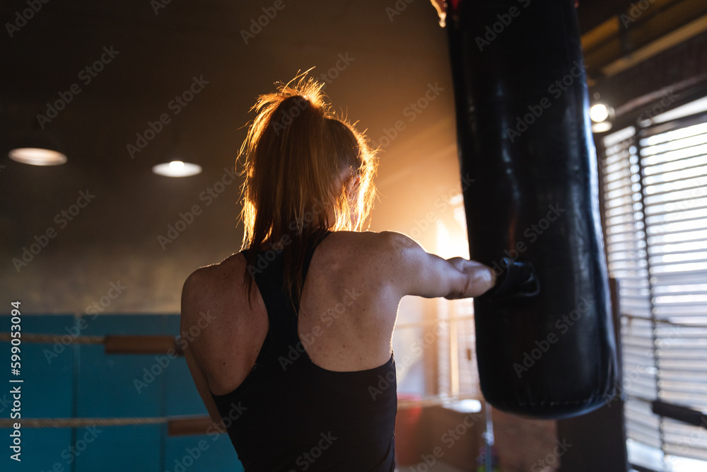 Women self defense girl power. Strong woman fighter training punches on boxing ring. Healthy strong girl punching boxing bag. Training day in boxing gym. Strength fit body workout training