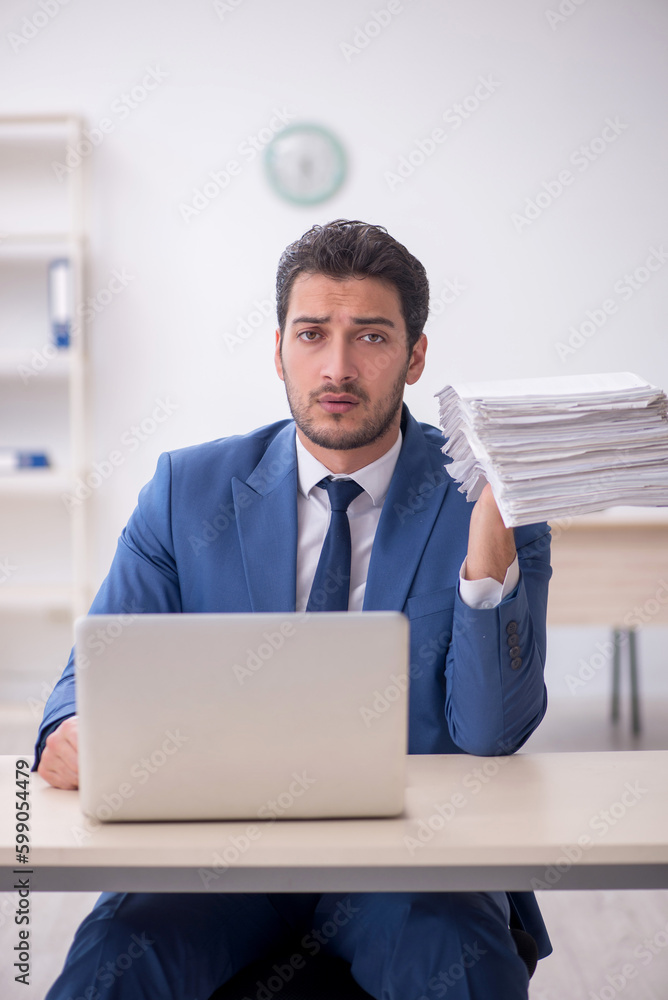 Young male employee and too much work in the office Young male employee and too much work in the office