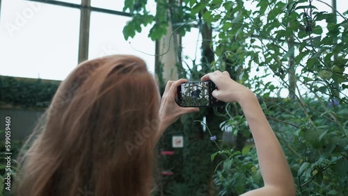 Woman taking a photo with a mobile phone of a flying butterfly.  Generative AI