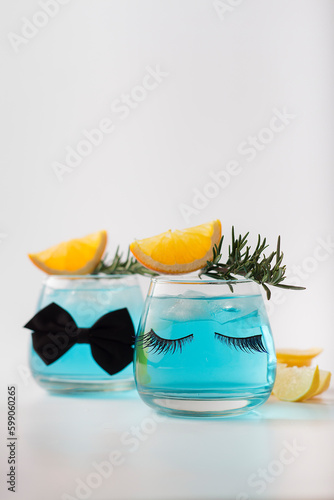 Summer cold drink closeup with drink splashing. Fresh cocktail with lemon, rosemary and ice in glass on white background. Studio shot of  blue cocktail. Focuse on eyelashes