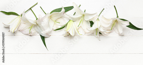 Delicate lily flowers on white wooden background, top view