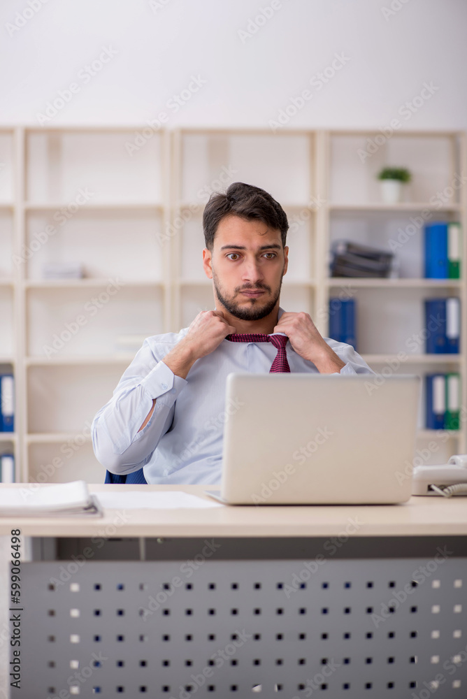 Young male employee sitting at workplace Young male employee sitting at workplace