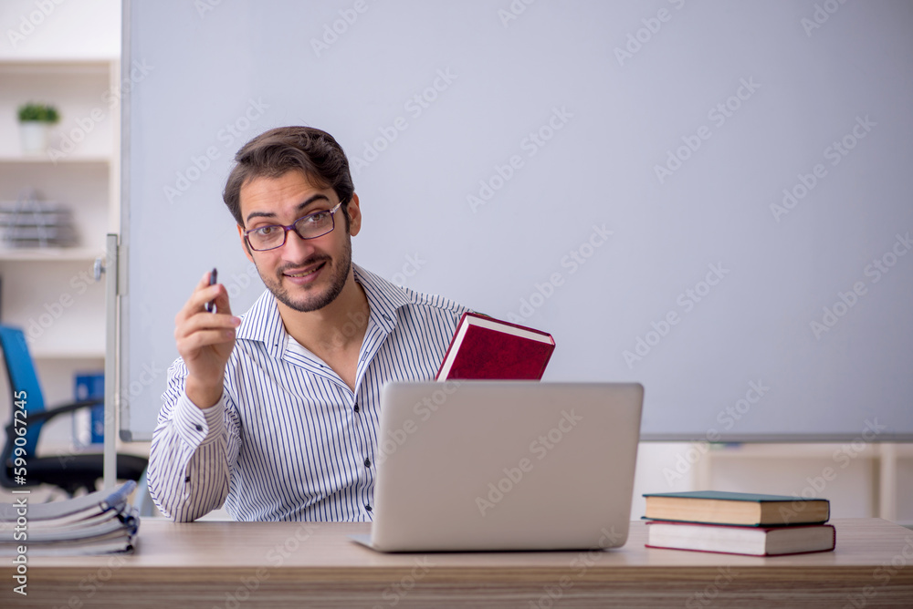 Fototapeta premium Young male teacher sitting in the classroom