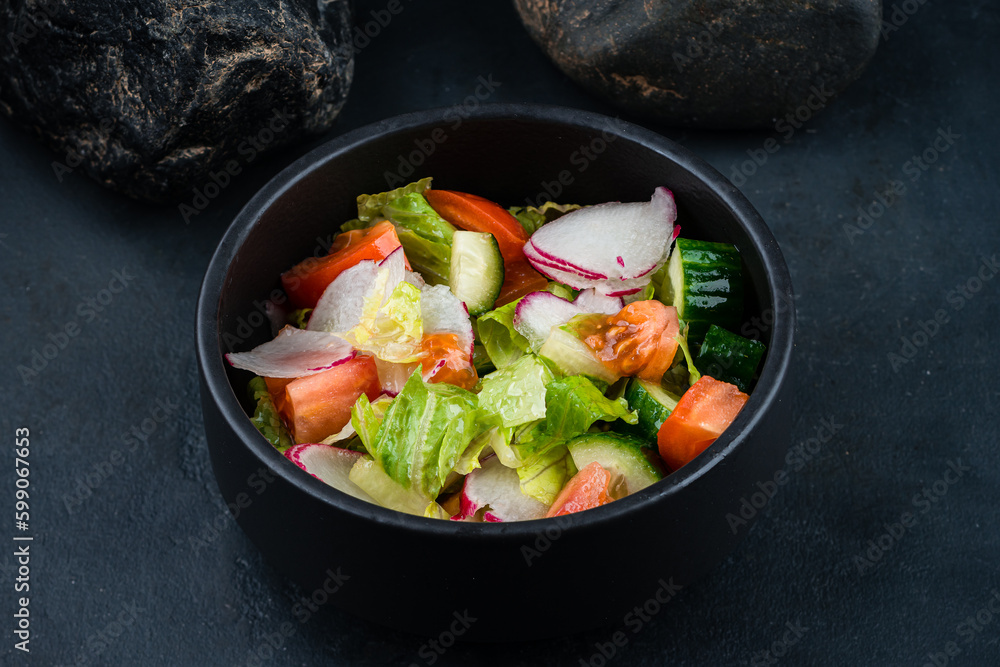 Green salad with cucumbers, lettuce, cherry tomatoes, and radish in a bowl.