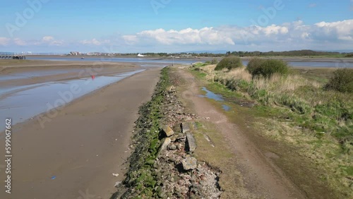 Flying along shoreline to solitary lamppost with lone figure at the River Wyre estuary Fleetwood Lancashire UK photo