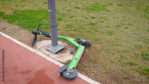 Rolling scooter. An electric scooter chained to a pole is lying on a bike path. Generative AI photo