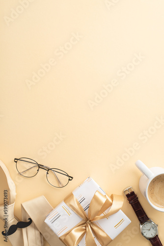 Show Dad some appreciation with an elegant Father's Day display idea. Top vertical view of tie, wristwatch, glasses, mustache, giftbox, coffee cup, on a beige background with an empty space for text