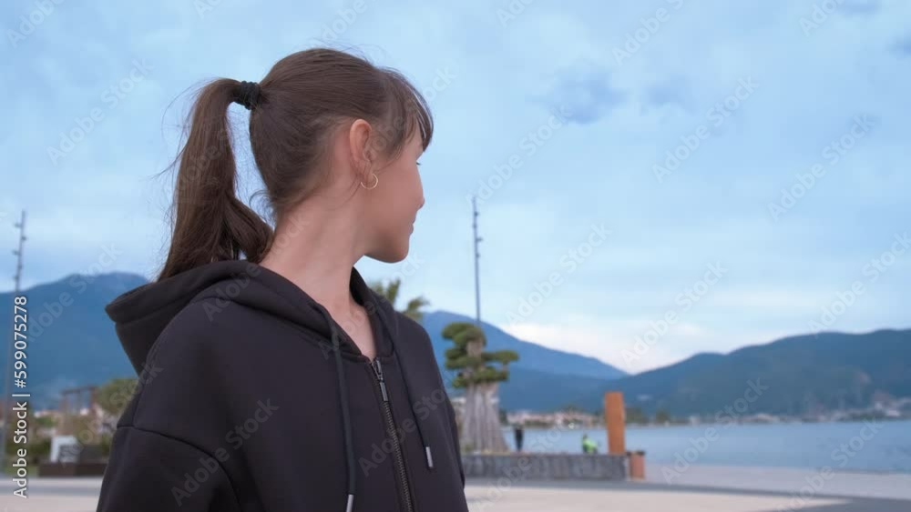 Happy young girl in a summer park against the backdrop of mountains. Teenage girl outdoors by the sea smiles sweetly. Generative AI Happy young girl in a summer park against the backdrop of mountains. Teenage girl outdoors by the sea smiles sweetly. Generative AI