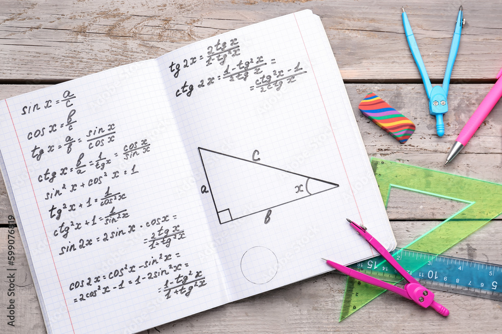 Fototapeta premium Copybook with maths formulas and stationery on grey wooden background