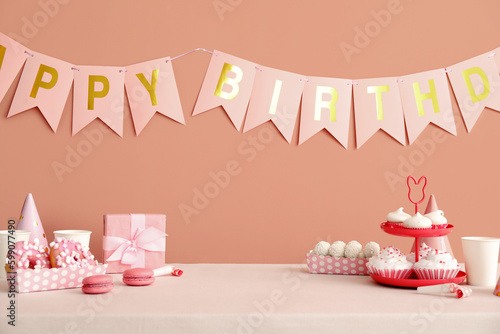 Photography Sweets on white table and happy birthday paper garlands on dark beige wall