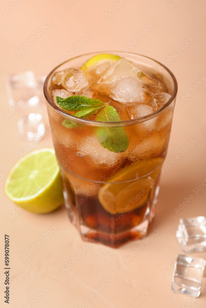 Glass of cold Cuba Libre cocktail on beige background Glass of cold Cuba Libre cocktail on beige background