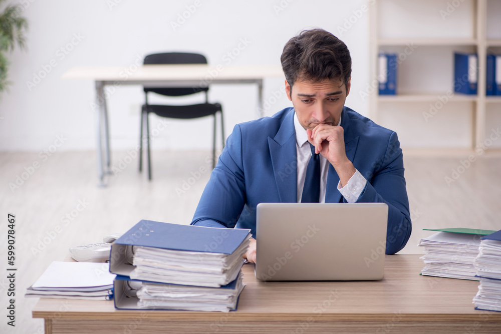 Young male employee and too much work in the office Young male employee and too much work in the office