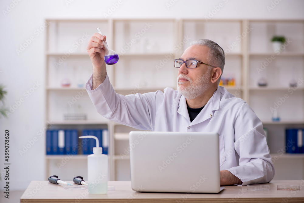 Old male chemist working at the lab