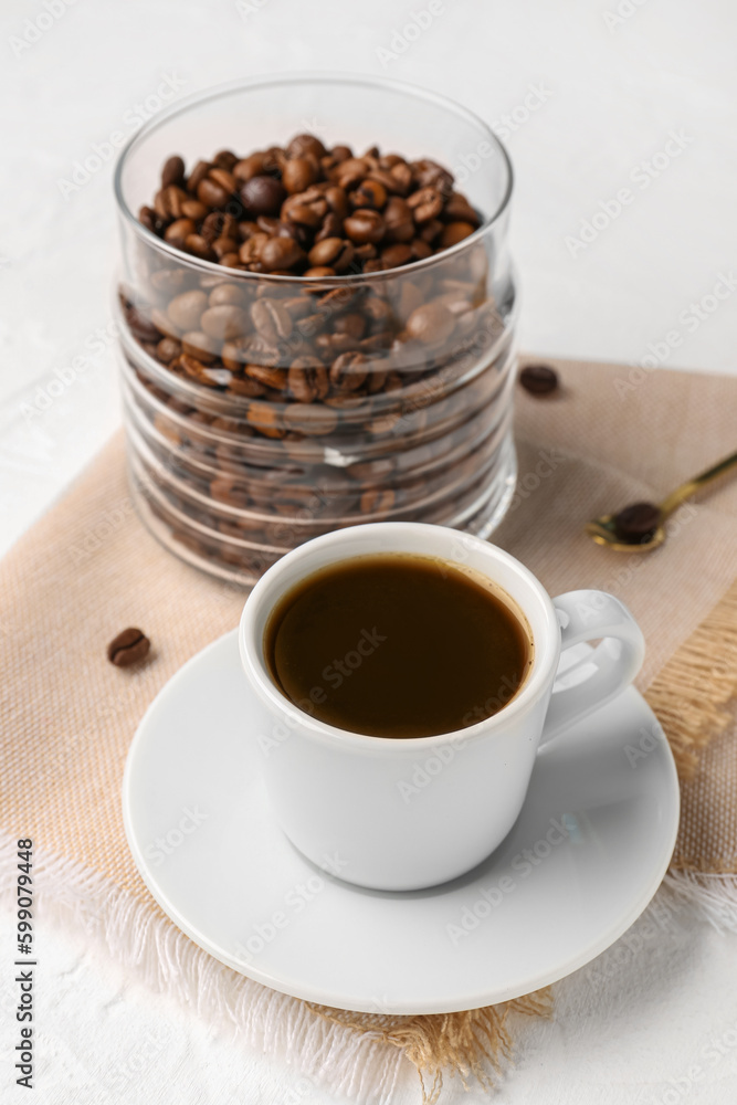Cup of coffee and jar with beans on light background Cup of coffee and jar with beans on light background