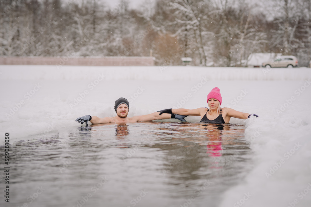 Winter swimming. Man and women in frozen lake ice hole. Swimmers wellness in icy water. How to swim in cold water. . white hat and gloves swimming clothes. Nature lake Winter swimming. Man and women in frozen lake ice hole. Swimmers wellness in icy water. How to swim in cold water. . white hat and gloves swimming clothes. Nature lake