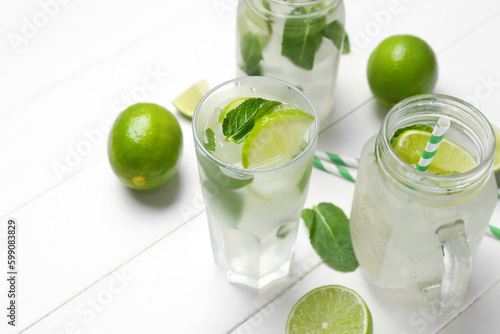 Mason jar and glass of tasty mojito on light wooden background