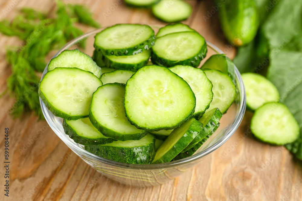 Bowl with pieces of fresh cucumber on wooden background Bowl with pieces of fresh cucumber on wooden background