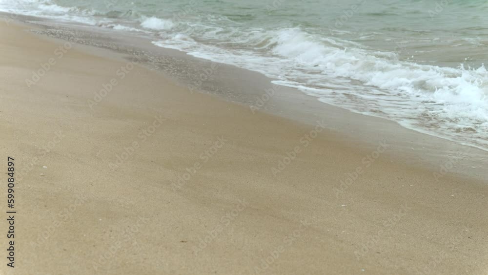 Slow motion of calm sea waves rolling on sandy beach on cold cloudy day. End of seasonal tourism, travel in winter Slow motion of calm sea waves rolling on sandy beach on cold cloudy day. End of seasonal tourism, travel in winter