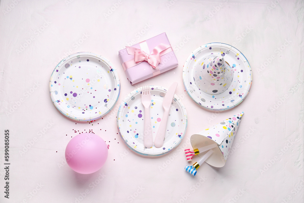 Paper disposable plates with gift, party hats and balloon on white background