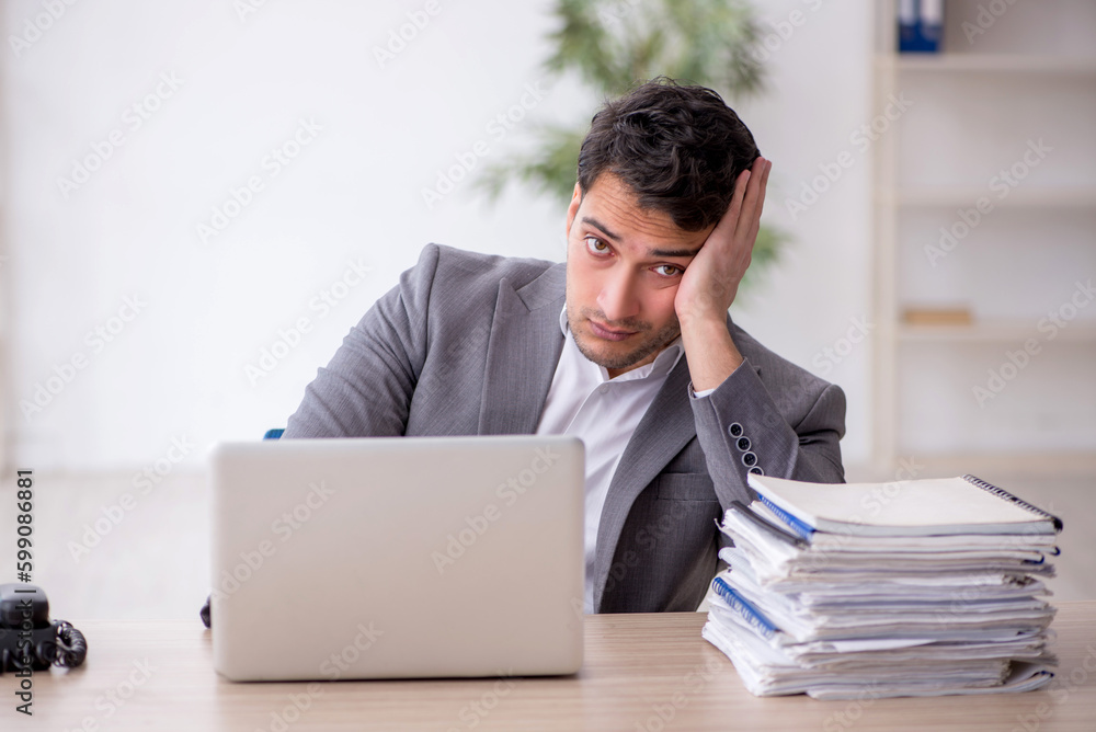 Young male employee and too much work in the office Young male employee and too much work in the office