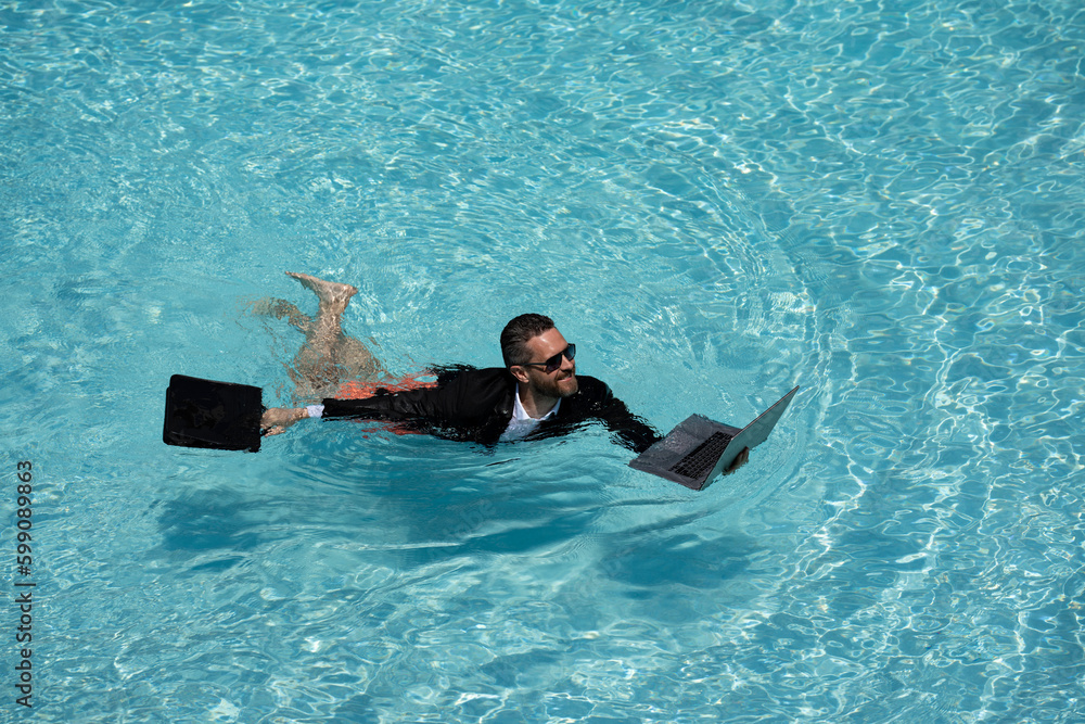 Funny business man relaxing in suit on swimming pool. Summer vacation, business on sea beach. Summer rest, business people concept. Wealthy business man relaxing in swimming pool. Remote on-line work.