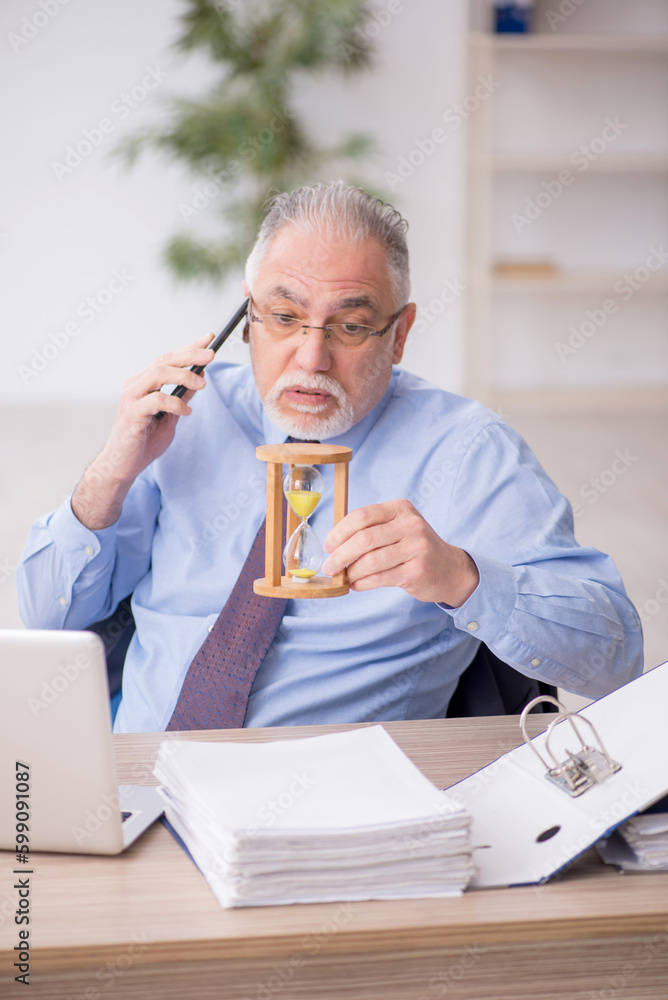 Old male employee in time management concept Old male employee in time management concept