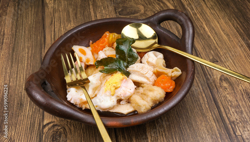 Indonesian street food cuisine, seblak in traditional wok pan, over wooden table photo