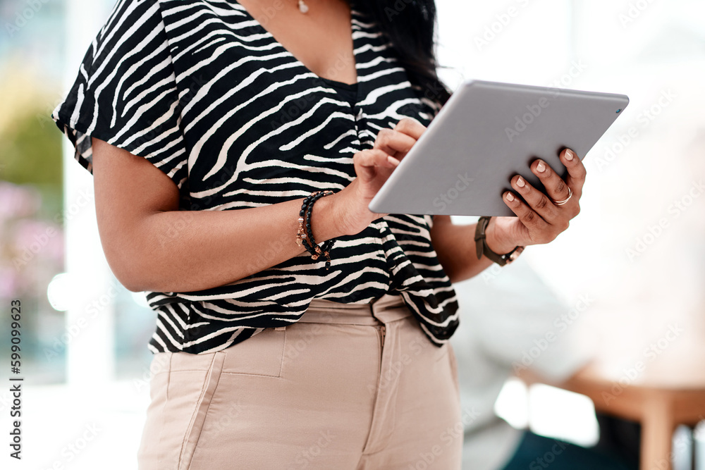 Technology is the perfect business aid. an unrecognizable young businesswoman using a tablet while standing in her office. Technology is the perfect business aid. an unrecognizable young businesswoman using a tablet while standing in her office.