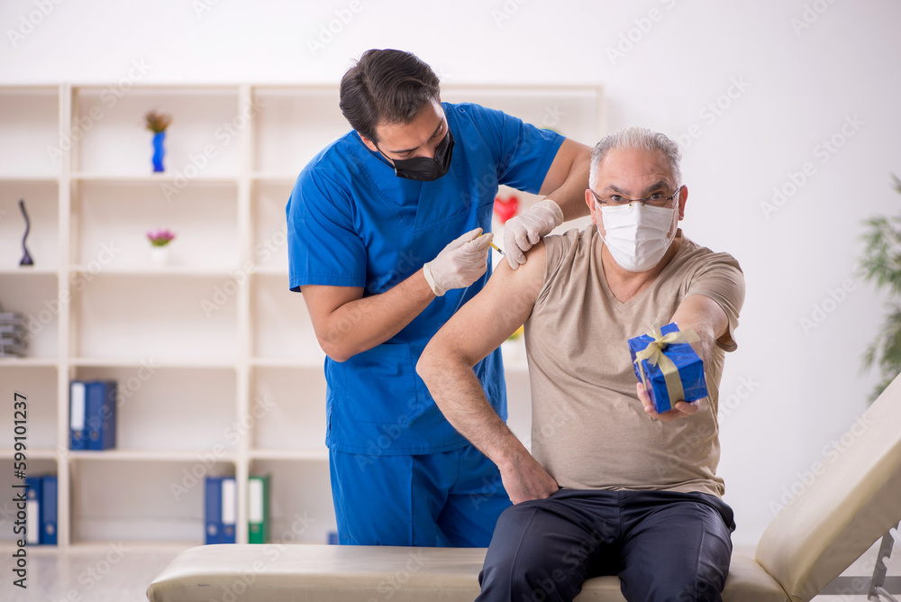 Young male doctor giving giftbox to old male patient Young male doctor giving giftbox to old male patient