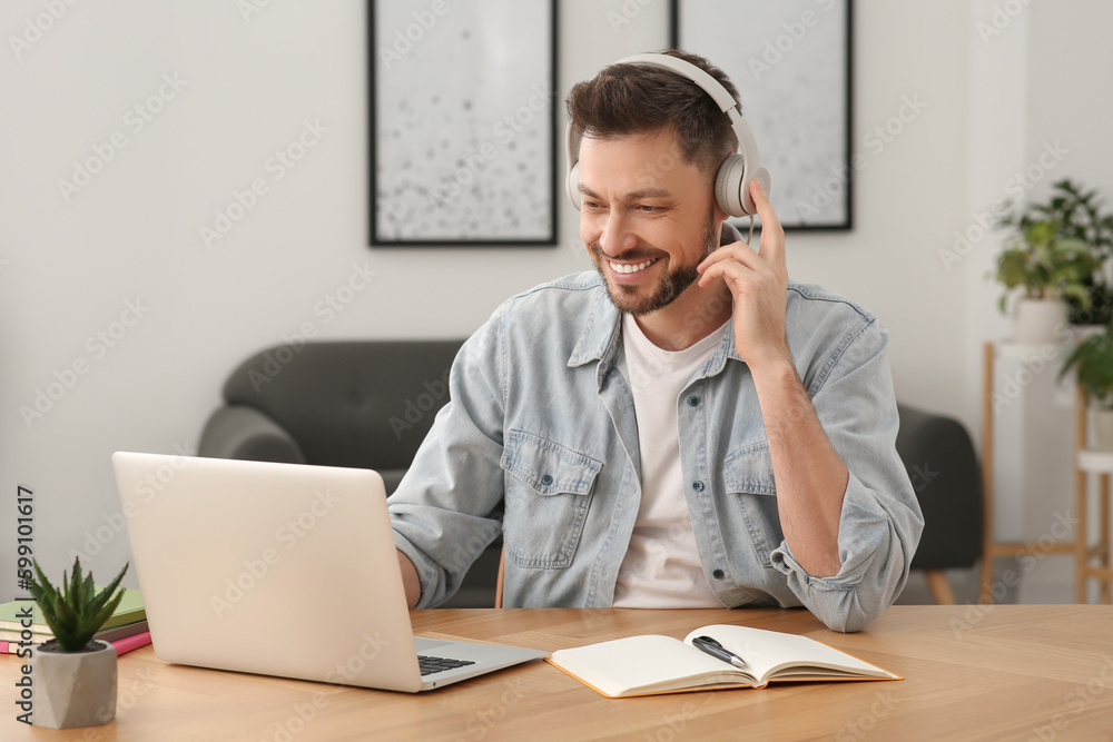 Man in headphones studying on laptop at home. Online translation course Man in headphones studying on laptop at home. Online translation course