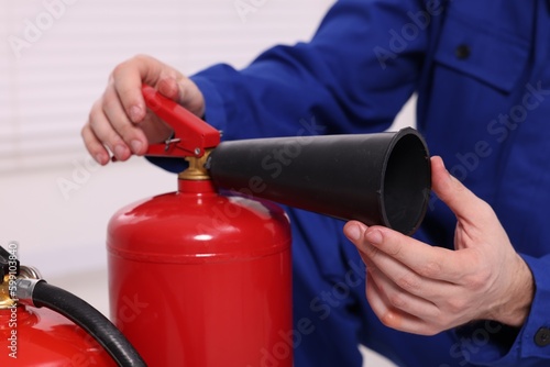 Man checking quality of fire extinguishers indoors, closeup