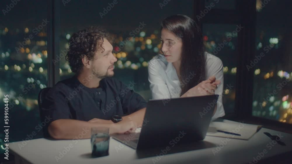 Medium shot of European family talking about work behind laptop, illuminated by the screen Medium shot of European family talking about work behind laptop, illuminated by the screen