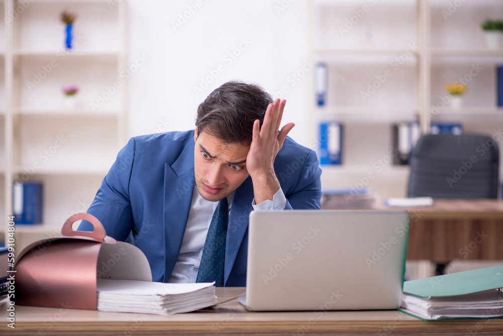 Young male employee eating cake at workplace Young male employee eating cake at workplace