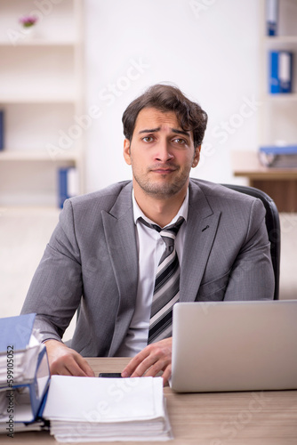 Young male employee unhappy with excessive work in the office