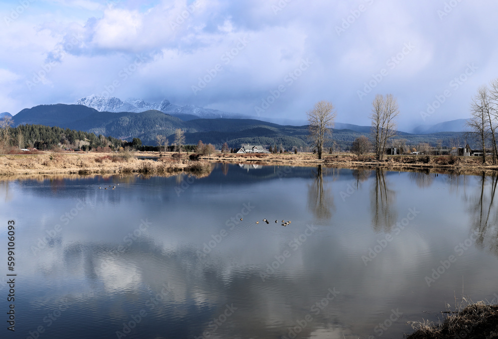 Afternoon winter scenery with dark clouds and calm pond
