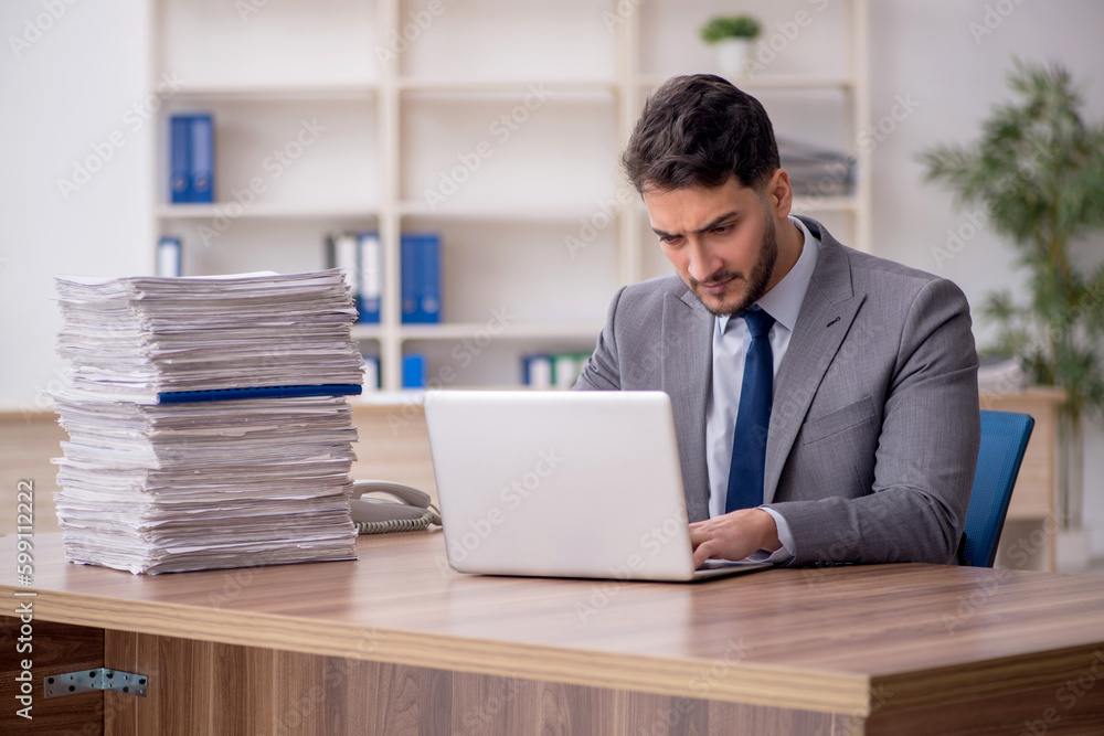 Young male employee and too much work in the office Young male employee and too much work in the office