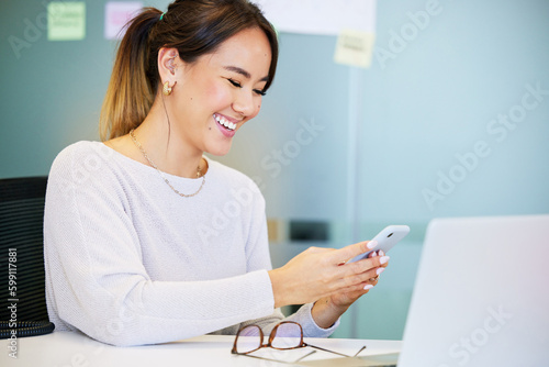 I have such funny clients. an attractive young businesswoman sitting alone in the office and using her cellphone.