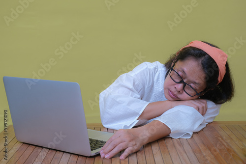 A middle-aged Asian woman falls asleep while working on her laptop. photo