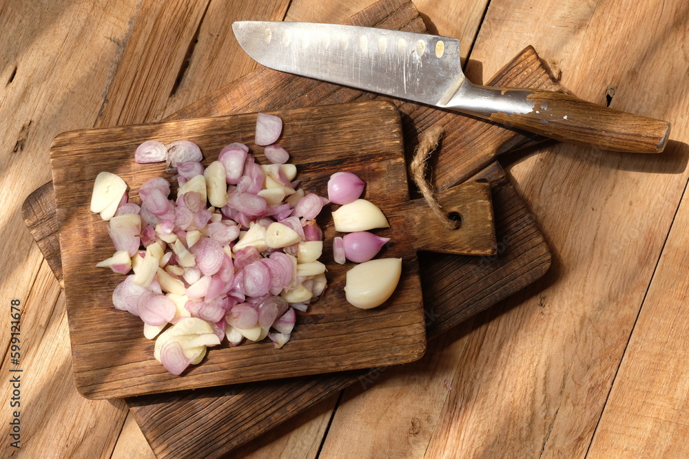 sliced red onion on a teak wood cutting board. stainless steel blade. spices. Allium cepa . allium sativum. sliced red onion on a teak wood cutting board. stainless steel blade. spices. Allium cepa . allium sativum.