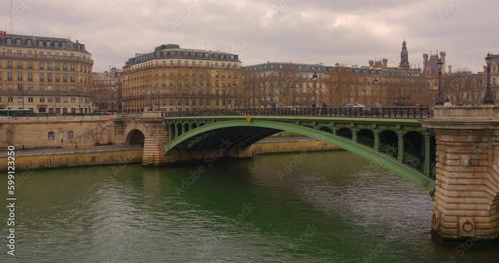 People And Vehicles Passing Across The Pont Notre-Dame Over Seine River With Buildings In Distance In Paris, France. static People And Vehicles Passing Across The Pont Notre-Dame Over Seine River With Buildings In Distance In Paris, France. static