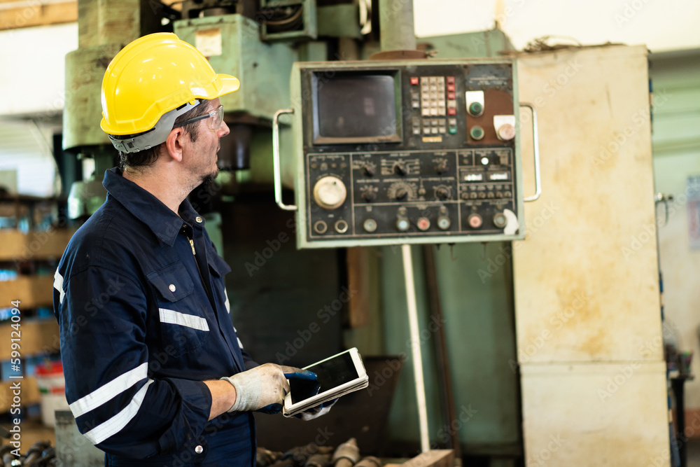 Professional caucasian white ethnicity male technician operating the heavy duty machine in the lathing factory. Technician in safety and helmet suit controlling a machine in factory. Professional caucasian white ethnicity male technician operating the heavy duty machine in the lathing factory. Technician in safety and helmet suit controlling a machine in factory.