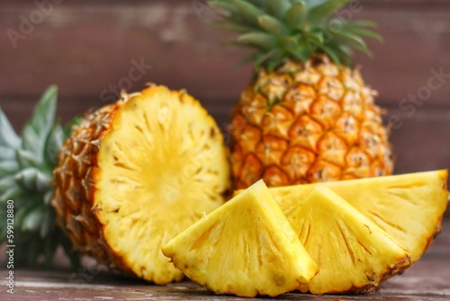 Close up at sliced and half of Pineapple(Ananas comosus) on wooden table with background.Sweet,sour and juicy taste.Have a lot of fiber,vitamins C and minerals.Fruits or healthcare concept.
